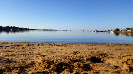 sand empty beach on a blue laggon at a greek island with boats