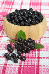 Fruits of black chokeberry on a bamboo bowl on the table