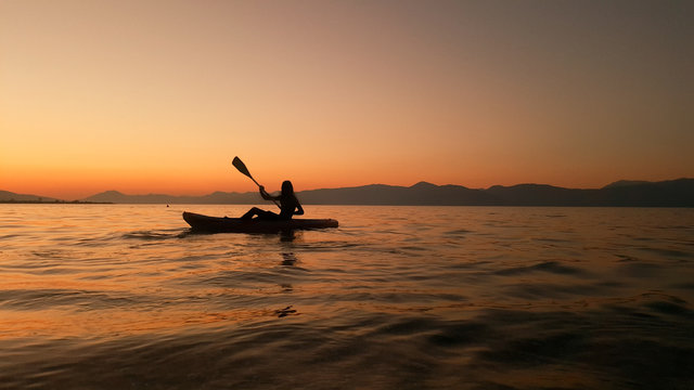 man rowing and a conoe at the calm water a summer evening in the ocean at greece