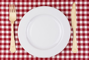 checkered tablecloth in red and white with wooden fork and knife and porcelain plate