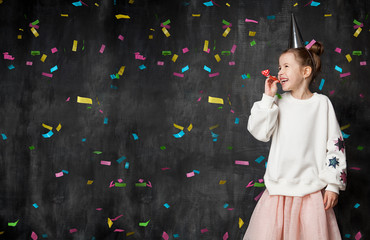 Little girl laughs and has fun at a celebration on the background of a school board and confetti with a free place on the left © deniskomarov