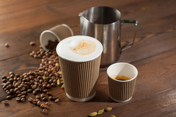 Latte and espresso in paper cups on a wooden background with scattered coffee beans