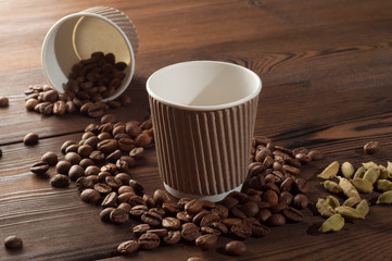Espresso in paper cup on a wooden background with scattered coffee beans