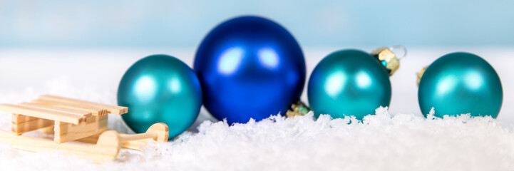 Holzschlitten im Schnee mit Weihnachtskugeln in Blau, Header