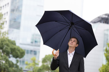 Middle aged businessman putting up an umbrella.