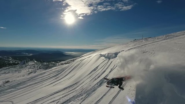 Slow Motion Aerial of the guy rolling around and jumping on a snowmobile from the eaves in the winter on the mountain