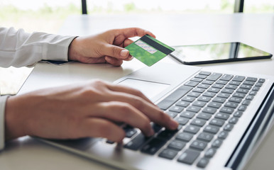 Business woman holding credit card entering security code and using laptop computer and digital tablet, online shopping concept