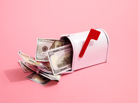 Mailbox containing US Dollar Bills with red flag on pink background