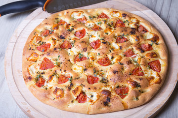 Fresh bread focaccio with cheese brynza and tomatoes. Homemade baking. Traditional Italian bread. Close-up, selective focus.
