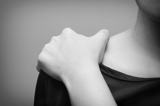 Young woman suffering from pain in shoulder,  Pain in the human body on a gray background- Black and white