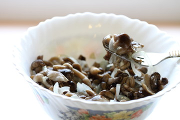 Delicious marinated mushrooms with onions in a plate, on a fork