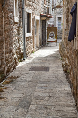 Old Town Street Budva, Montenegro. We see ancient houses, a very narrow street, cafes, shops.