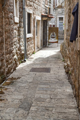 Obraz premium Old Town Street Budva, Montenegro. We see ancient houses, a very narrow street, cafes, shops.