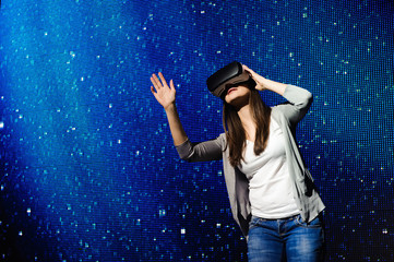 Fototapeta na wymiar a beautiful girl wearing a virtual reality device, standing on the background of the sky