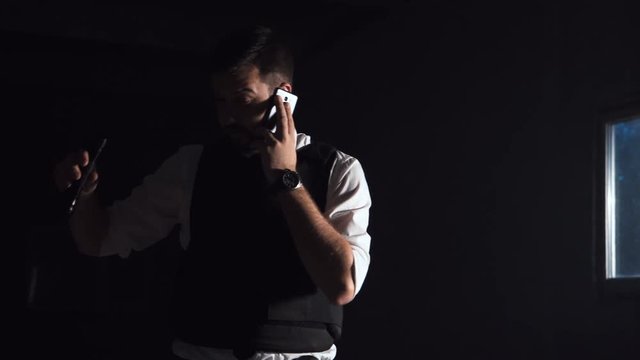 Vigilant and courageous police investigator talking on mobile phone while searching for a dangerous suspect indoor in the night