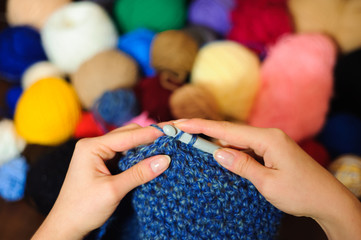 Colorful yarn stacked in a series of colors. Balls and skeins of colored yarn for knitting. A woman going to knit.