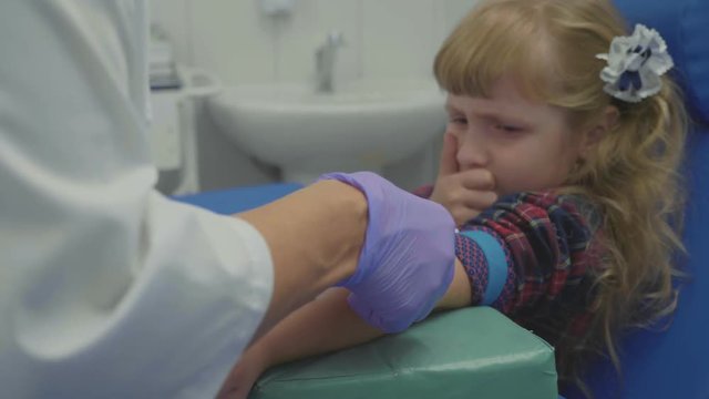 Nurse is taking blood sample from a vein in the arm of little girl