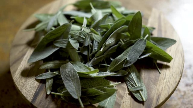 Sage leaves on a wooden cuttng board rotating in beautiful backlit light.