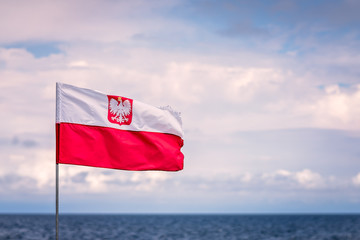 Red and white Polish flag with Baltic sea in the background