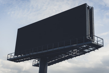 Black billboard against bright blue sky.