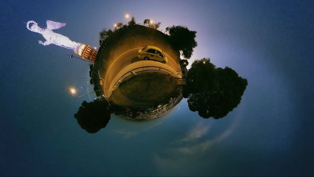A spherical 360 tiny-planet night view of the illuminated Virgin of El Panecillo statue in Quito, Ecuador, a winding road with a yellow car and trees under a dark starry sky.