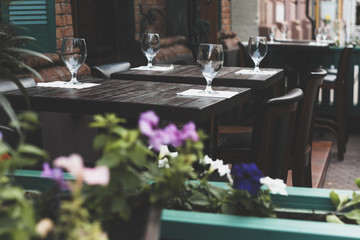 Empty wineglasses in restaurant on the table outside. Decoration flowers background.