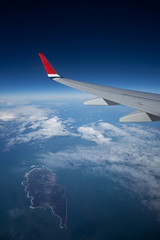 Fototapeta na wymiar Blick aus dem Flugzeug auf den Ozean mit Cumulus Wolken und Insel