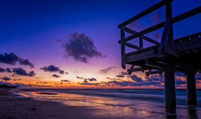 Sunset over wooden pier on the sea beach