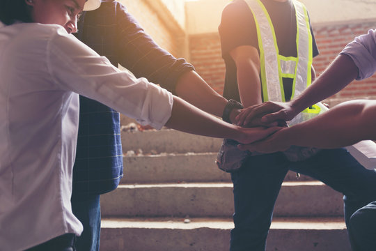 Team engineers and workers combine hands to express unity.
