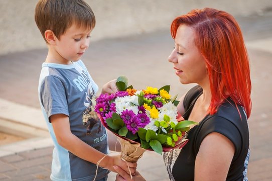Cute Caucasian boy handing a flower bouquet to his mother. Mother's day illustration.