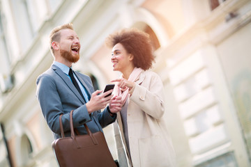 Happy business couple using smart phone outdoors