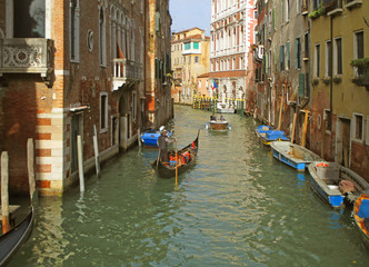 Fototapeta na wymiar Small Canal of Venice with the Gondola and Another Watercraft on a Sunny Afternoon, Italy 