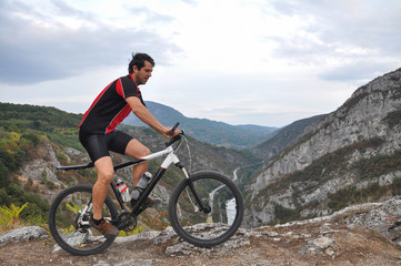 Fototapeta na wymiar Young man riding a bike on rocks on the mountain, extreme riding bicycle off road on rocks