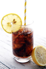 Softdrink with ice cubes, lemon and straw in glass