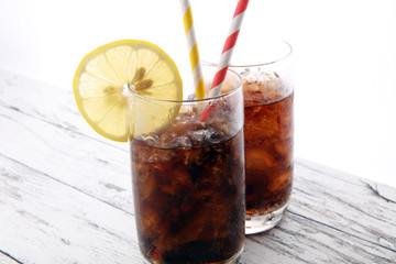 Softdrink with ice cubes, lemon and straw in glass