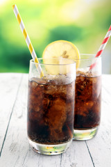 Softdrink with ice cubes, lemon and straw in glass