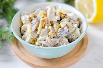 Christmas salad from chicken, potatoes, marinated mushrooms and pickles with parchment from Dijon mustard