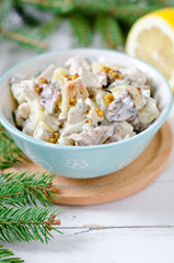 Christmas salad from chicken, potatoes, marinated mushrooms and pickles with parchment from Dijon mustard