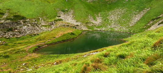 Panoramic photo of a mountain lake in a mountainous rocky valley. Serene lake Berbeneskul, Carpathians, Ukraine. Great view of Montenegrin Range above beautiful serenity lake.