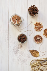 Autumn pattern with yellow leaves and dried orange slices on  white wooden background. 