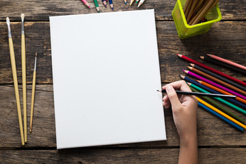 Girl hand drawing, empty paper and colorful pencils on old wooden table