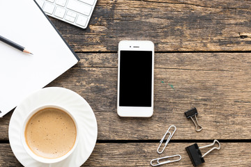 close up smart phone with coffee cup and  computer on wooden table top view.