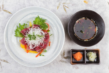 Top view of Sliced medium rare wagyu topping with sliced radish and scallion served with mince radish, carrot and Ponzu sauce on washi (Japanese paper).