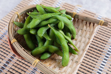 Frozen edamame beans in the basket on makisu (meal mat) ready to serve at Japanese restaurant in Bangkok, Thailand.