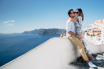 Happy couple hugging and laughing together with a view of Santorini - obrazy, fototapety, plakaty
