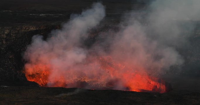 Kilauea Volcano crater violent lava eruption night Hawaii. Most active volcano in USA. Smoke, steam, gasses. Big Island Volcano National Park. Eruptions and lava flow continually. Geological crater.