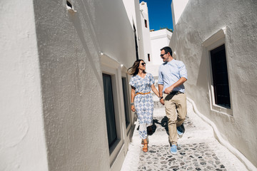 Happy couple walking and laughing together with a view of Santorini