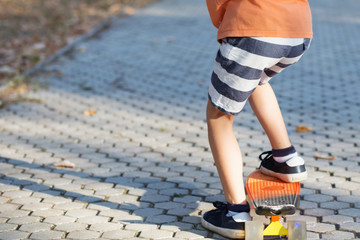 Little urban boy with a penny skateboard. Young kid riding in the park on a skateboard. City style. Urban kids. Child learns to ride a penny board