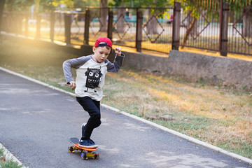 Little urban boy with a penny skateboard. Young kid riding in the park on a skateboard. City style. Urban kids.
