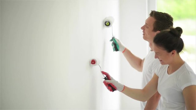 Happy Family Paints the Wall with White Paint. Repair in the Apartment Concept.